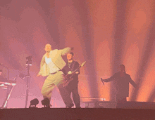 a man singing into a microphone on stage with a desert in the background