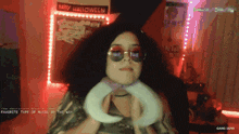 a woman wearing sunglasses stands in front of a sign that says " happy halloween "