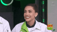 a woman is smiling in front of a sign that says hoy en la cocina