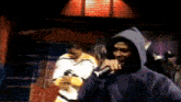 a man in a hooded jacket is holding a microphone