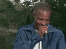 a man in a blue jacket is holding a microphone in his mouth and says que soco na cara .