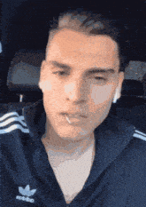 a man with a cigarette in his mouth wearing an adidas jacket