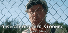 a man behind a chain link fence with the words dis motherfucker is looney