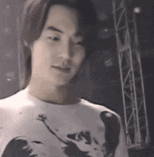 a man with long hair is wearing a white t-shirt with a picture of a monkey on it .