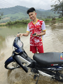 a young man stands next to a motorcycle that says honda
