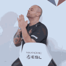 a man is praying in front of a chair that says maxnomic esl