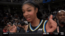 a female basketball player giving a thumbs up in front of a crowd with the espn logo in the corner