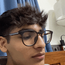 a young man wearing glasses is looking at the camera