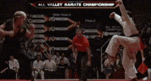 two men are fighting in front of a sign that says karate championship