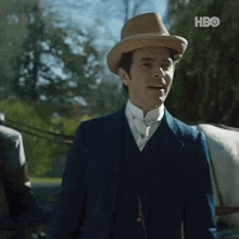 a man in a suit and hat is standing in front of a horse drawn carriage with hbo written on the bottom