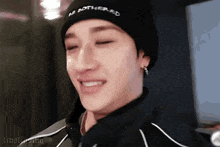 a close up of a person wearing a black beanie and earrings .