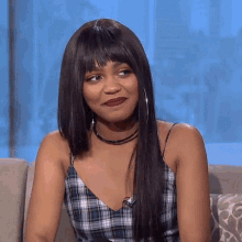 a woman in a plaid top and choker is sitting on a couch .