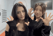 a couple of women standing next to each other with their hands in the air