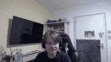 a young man wearing headphones is sitting in a chair in front of a television .