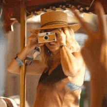 a woman in a straw hat takes a picture with a small camera