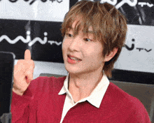 a man in a red sweater giving a thumbs up