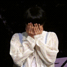 a person covering their face with their hands with a black background