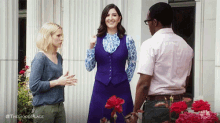 a man and two women are standing next to each other in front of a building .