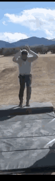 a man is jumping on a mat in a field