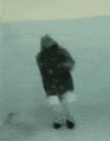 a blurry picture of a person standing in front of a wall .