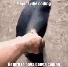 a person is holding a black object with the words reject vibe coding return to ooga booga coding below it