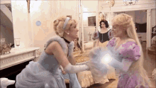 cinderella and rapunzel are standing next to each other in a room holding hands .