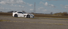 a white sports car is driving down the road