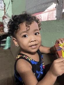 a little girl with curly hair is holding a box with a picture of a man on it