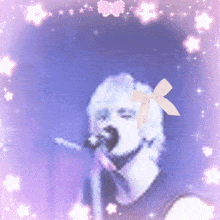 a woman singing into a microphone with a pink bow