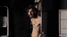 a man without a shirt is standing in front of a mirror .