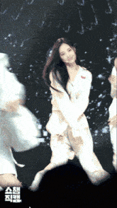 a woman in a white outfit is dancing in front of a sign that says ' ash '