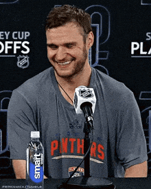 a man sitting in front of a microphone wearing a shirt that says panthers on it