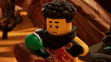 a close up of a lego character holding a green item