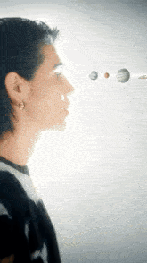 a man in a black shirt is looking at the planets of the solar system