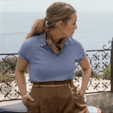 a woman wearing a blue polo shirt and brown pants