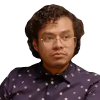 a man with curly hair and glasses is wearing a purple shirt with white polka dots