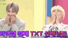two young men are sitting next to each other with their hands on their faces and laughing .