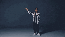 a man in a suit is dancing in a dark room while holding a microphone