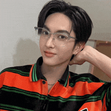 a young man wearing glasses and a striped shirt looks at the camera
