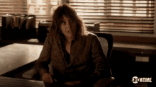 a woman is sitting at a desk with showtime written on the bottom right