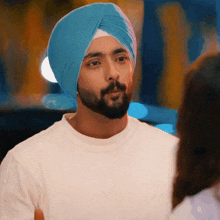 a man wearing a turban and a white shirt is looking at a woman .