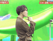 a man in a brown jacket is standing in front of a green background with a sign that says snow