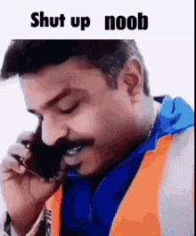a man is talking on a cell phone while wearing an orange vest and a blue jacket .