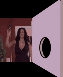 a woman in a black dress is standing in front of a white wall with a crescent moon on it
