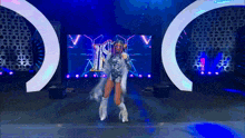 a woman is dancing on a stage in front of a large screen that says i
