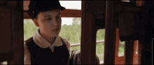 a young girl wearing a hat is looking out a window