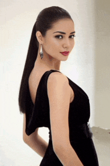 a woman in a black dress has a ponytail and earrings