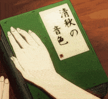 a person 's hand rests on a book with chinese writing on it