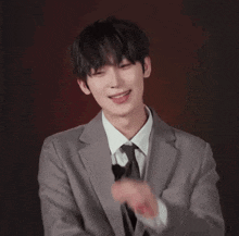 a young man in a suit and tie is smiling and clapping his hands