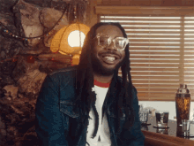 a man with dreadlocks and glasses is sitting at a bar